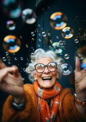 A joyful elderly woman plays with soap bubbles. Portrait of a smiling grandmother with foam bubbles.