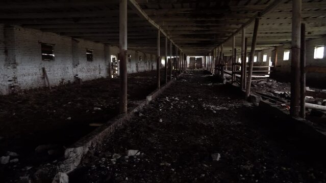 Abandoned ruined barn cowshed inside view. The old abandoned barn with the remains of feeders. barn from inside with low light