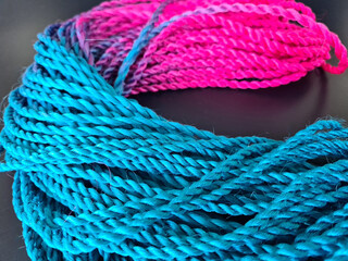 Colored braids with bright pink and blue elastic bands on a black background