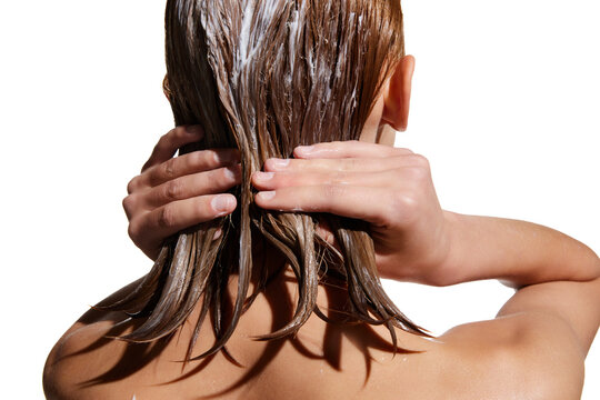 Back view of girl with wet hair, applying hair mask against white studio background. Conditioner treatment, nutrition. Concept of beauty, hair care, treatment, natural cosmetics. Copy space for ad