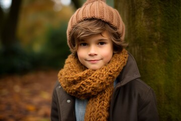 Outdoor portrait of adorable little boy wearing warm hat and scarf in autumn park