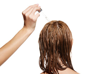 Female hand applying oil, serum on wet hair for repairing damaged hair against white studio...