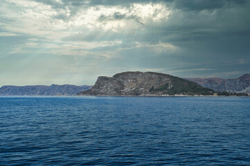 Fototapeta na wymiar Fjord with mountains on horizon. Water glistens in the sun in Norway. Landscape