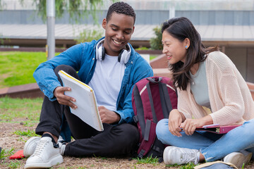 smiling multiracial college students outdoors preparing for exam.
