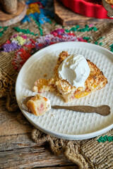 Peach and plum streusel pie with ice cream, side view, wooden background, rustic.