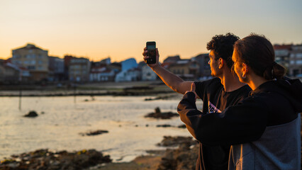 young friends taking a selfie with smartphone during sunset