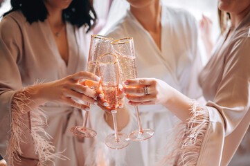 Close-up of female hands holding glasses with champagne. Women in bathrobes drinking champagne