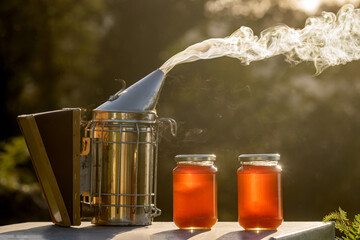 Two small jars of ecological honey on a hive next to a smoker