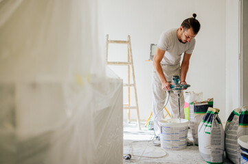 A worker is mixing plaster with manual cement mixer and renovating home.