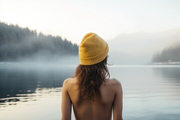 Young woman in a hat bathing in the cold water of the lake. Wim Hof method, cold therapy, breathing techniques, winter swimming, ice swimming. - obrazy, fototapety, plakaty