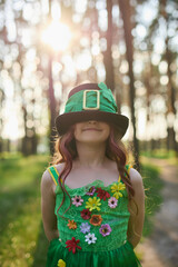 Adorable little girl in a leprechaun costume. Cute redhead child in cylinder har and green fairy...