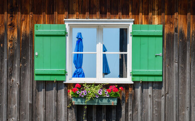 Wooden window decorated with flowers. Stilt house on the shore of Lake Constance (Bodensee) in Bregenz, public swimming bath.