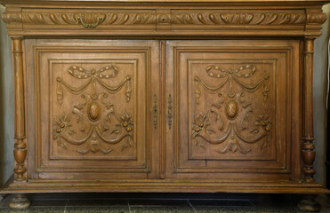 Old vintage wardrobe furniture with ornamental doors and retro colors of wooden surfaces close up