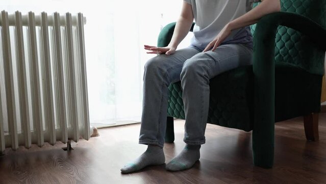 Close-up of nervous woman sitting in velvet armchair and rubbing her leg trembling from stress. Concept of anxiety and OCD
