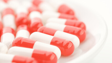Gelatin red white capsules in white plate. Pharmaceutical Industry concept