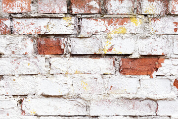 Old brick wall with white cracked paint. Rough brick wall texture. Abstract brick wall background for design. Close up.