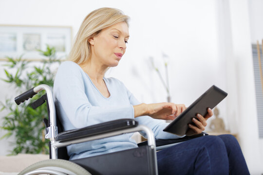 happy mature woman in wheelchair using interent assistance