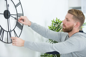 young man setting a large mechanical clock