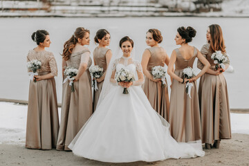 The bride and her bridesmaids pose holding bouquets and looking over their shoulders