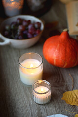 Cup of tea or coffee, plate with desserts, dried oranges, bowl of grapes, scented candles, vintage books, pumpkins and autumn leaves on the table. Autumnal hygge. Selective focus.