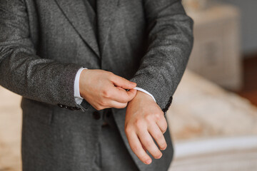 Obraz premium A man poses and adjusts a gray jacket. Portrait of the groom. Fashion and style. Business