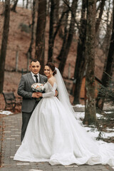 Fototapeta na wymiar Portrait. The bride and groom are standing, holding a bouquet, posing in the forest. A walk in the forest. Winter wedding