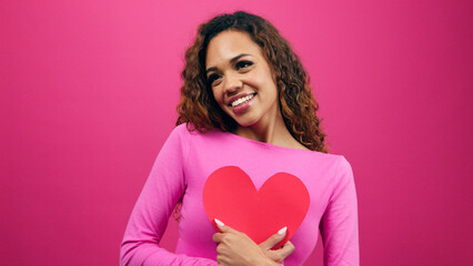 Beautiful young woman in love, hugging heart self love, pink studio Valentines