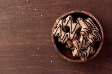 Homemade star-shaped cookie with chocolate in the wooden bowl on the brown wooden table with copy space