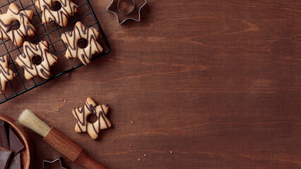Wooden background with fresh baked homemade star-shaped cookie with chocolate on the grid