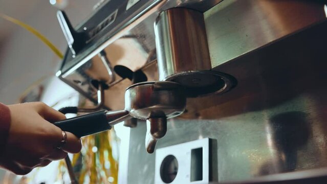 Modern coffee machine. Female barista worker taking portafilter for coffee preparation. Slow motion. Concept of coffee industry, occupation, taste, coffee shop, cafeteria, business