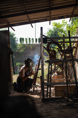 Side view of a welder working on a decorative grille.