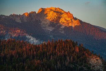 An orange mountain peak of Sierra Nevada mountains viewed from Moro Rock in Sequoia National Park during sunset. - obrazy, fototapety, plakaty