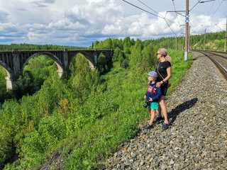 Railway bridge across the river in the south of the Kama region. A girl with a child on the...