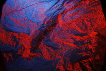 Bollo de papel tissue  absorbente y arrugado para la higiene de manos y limpieza del hogar   iluminado con luz roja y azul, forma una superficie texturizada abstracta para fondos - obrazy, fototapety, plakaty