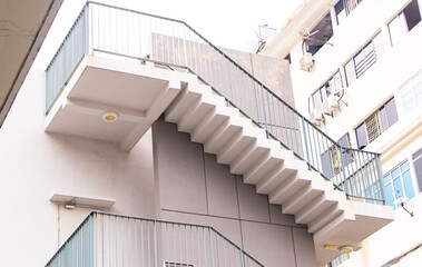 Structure white concrete stairs on side of building or apartment. Evening sun shines with white...