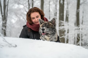 Caucasian female with her furry dog in the forest covered in the blanket of snow