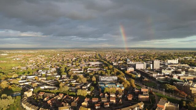 Aerial view flying towards the double rainbow arching over Basildon town centre