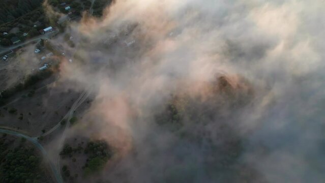 Golden clouds and fog during sunrise revealing southern France landscape. Aerial overhead shot.