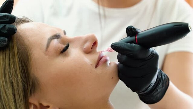 Young woman having permanent makeup on lips in beautician salon