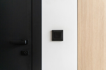 Black interior door in living room with light switch and wooden cabinet