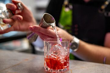 bartender hand making negroni cocktail in bar