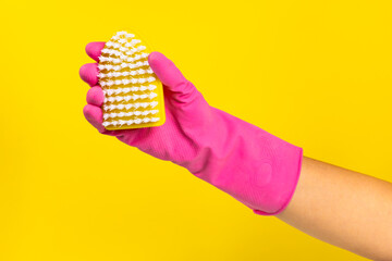 Brush for cleaning in hand. Women's hand cleaning on a colored background. Cleaning or housekeeping concepts.