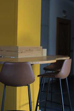 Area de descanso en oficina. Butacas marrones y barra de madera en pilar amarillo. Paneles grises al fondo