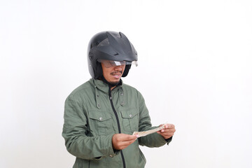 Happy asian man wearing helmet and jacket holding STNK/Surat Tanda Nomor Kendaraan or Indonesian Vehicle registration certificate