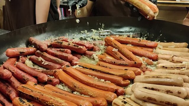 Street food hot dog - grilled German or Bavarian Nuremberg sausages with cabbage sauerkraut on a huge pan bowl at market.