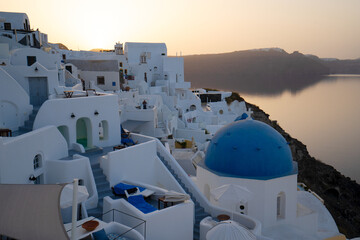 traditional greek village Oia of Santorini, with blue domes of churches and village roofs in soft...