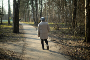 Elderly man walks through park. Pensioner walks through city. Old clothes on person.