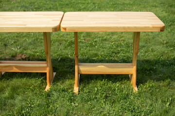 Wooden table on a green lawn. Wooden furniture in the park. Empty tables.