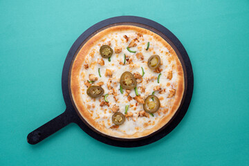 jalapenos toppings pizza with wooden pan on green background
