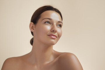 Skincare Beauty Spa Face of Woman with Healthy Skin, Natural Makeup .Young adult happy girl model with bare shoulders on beige background closeup. High-quality beauty product or treatment conceptual